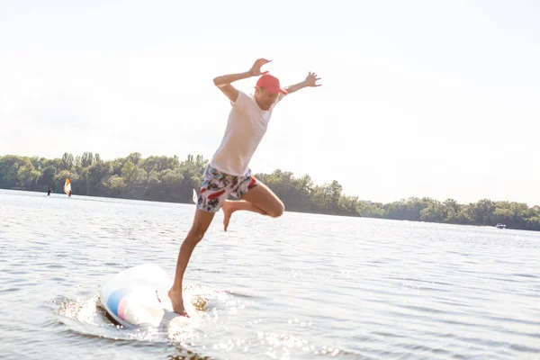 Retrato de un surfista con una tabla SUP en la playa. Joven en el paddleboard al amanecer. El concepto de deportes extremos. Estilo de vida del surfista masculino. —  Fotos de Stock