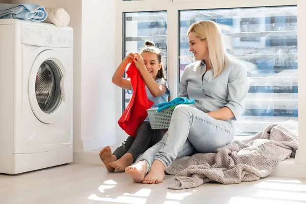Mladý hospodyňka a holčička dělá prádlo společně — Stock fotografie