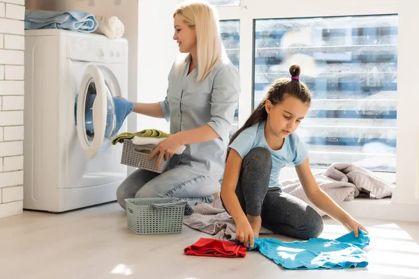 Genç ev hanımı ve küçük kız birlikte çamaşır yıkıyorlar. — Stok fotoğraf