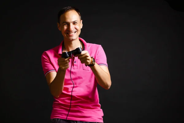 Um homem brinca com um joystick em casa em um fundo preto — Fotografia de Stock