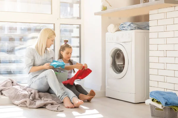 Feliz ama de casa y su hija con ropa de cama cerca de la lavadora — Foto de Stock