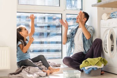 Mutlu Aile evde çamaşır makinesine çamaşır yüklüyor.