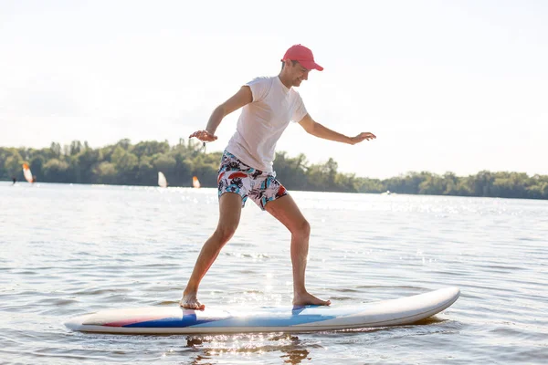 Silueta de stand up paddle boarder remando al atardecer —  Fotos de Stock