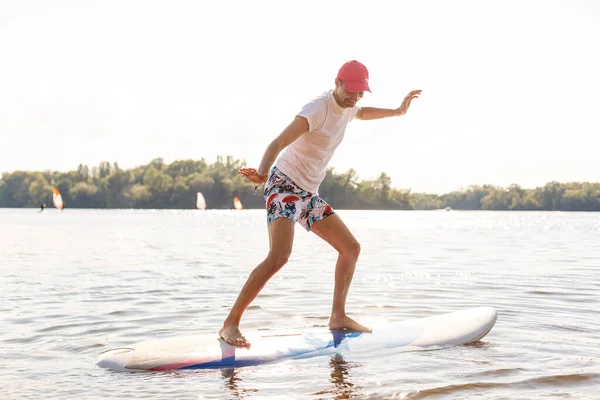 Silueta de stand up paddle boarder remando al atardecer —  Fotos de Stock