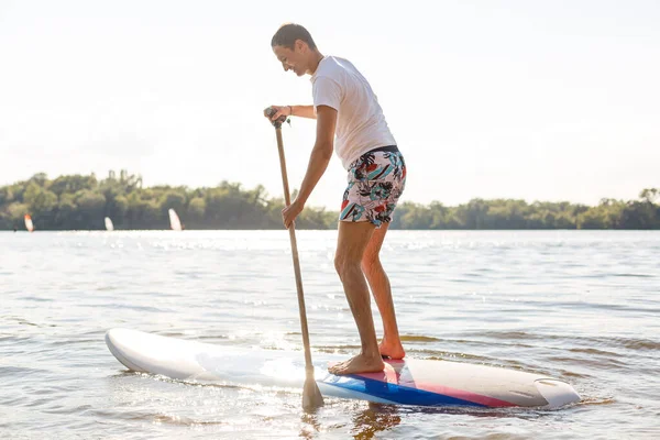 Silueta de stand up paddle boarder remando al atardecer —  Fotos de Stock