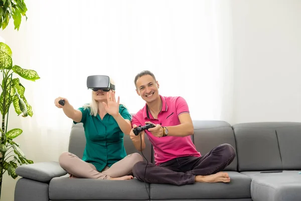 Young funny couple playing video games virtual reality glasses in their apartment - Happy people having fun with new trends technology - Gaming concept - Focus on woman joypad