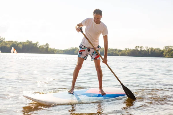 Silueta de stand up paddle boarder remando al atardecer —  Fotos de Stock