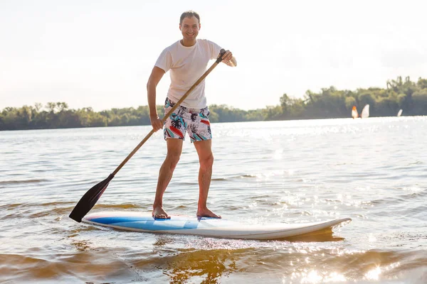 Silueta de stand up paddle boarder remando al atardecer —  Fotos de Stock