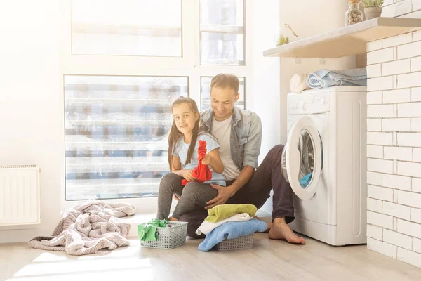 Familia feliz cargando ropa en la lavadora en casa — Foto de Stock