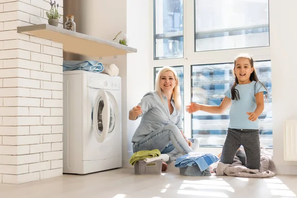 Mladý hospodyňka a holčička dělá prádlo společně — Stock fotografie