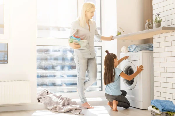 Rodina matka a dítě dívka malý pomocník v prádelně v blízkosti pračky a špinavé oblečení — Stock fotografie