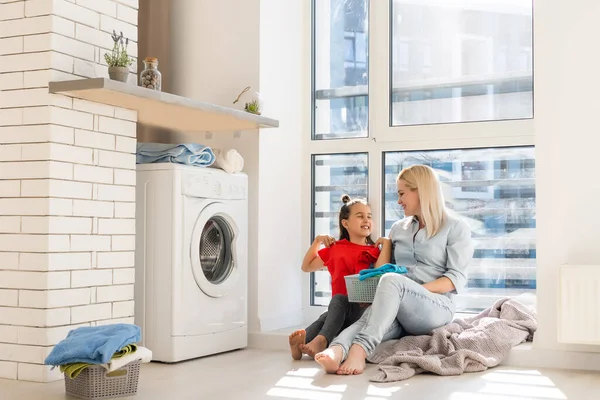 Feliz ama de casa y su hija con ropa de cama cerca de la lavadora — Foto de Stock