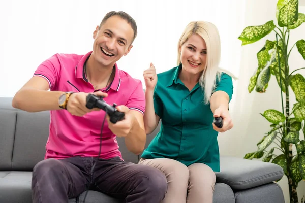 Mand og kvinde spiller videospil med joystick derhjemme. - Stock-foto