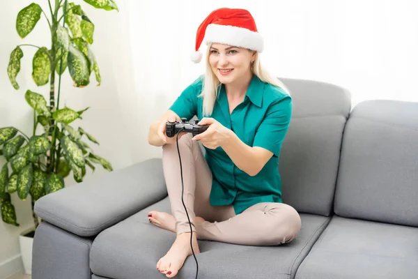 Weihnachten, Spiele, Urlaub, Feier und Technologiekonzept - Frau hält Gamepad in der Hand und spielt Videospiele zu Hause — Stockfoto