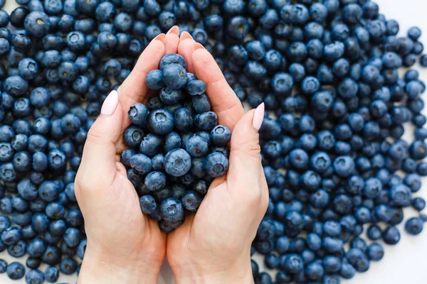 Large ripe blueberries in female hands on a gray background. A handful of blueberries. — Stock Photo, Image