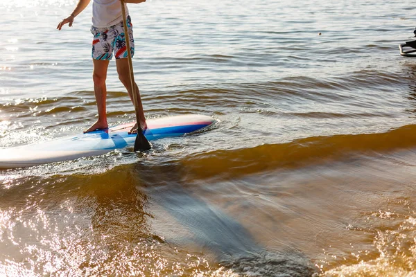 Silueta de stand up paddle boarder remando al atardecer — Foto de Stock