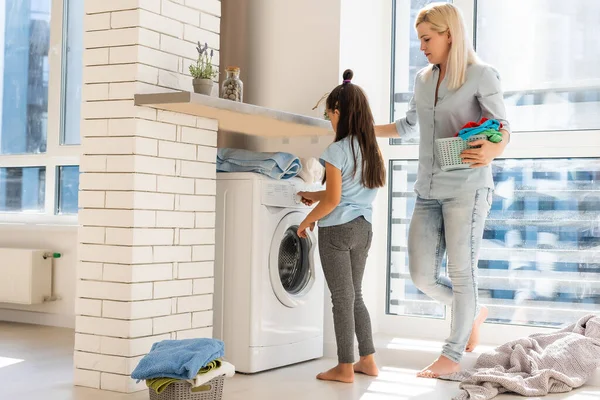 Ung hemmafru och liten flicka tvättar tillsammans — Stockfoto