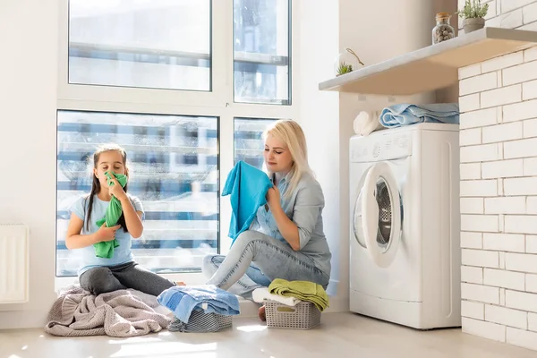 Boldog háziasszony és lánya ágynemű közelében mosógép — Stock Fotó