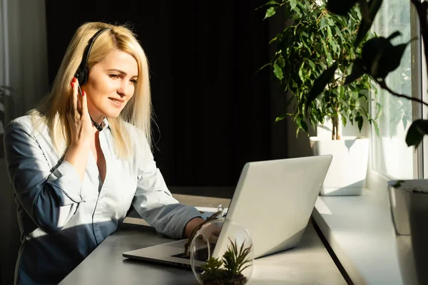 Portret van een serieuze casual zakenvrouw zittend aan tafel met laptop op kantoor en kijkend naar camera — Stockfoto