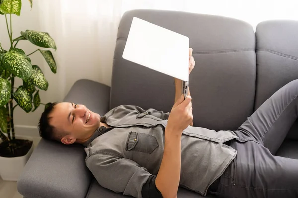 Technológia, otthon és életmód koncepció - közelkép az ember dolgozik laptop számítógép és ül a kanapén otthon — Stock Fotó