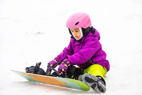 Μικρή χαριτωμένο κορίτσι Snowboarding στο χιονοδρομικό κέντρο στην ηλιόλουστη μέρα του χειμώνα. — Φωτογραφία Αρχείου