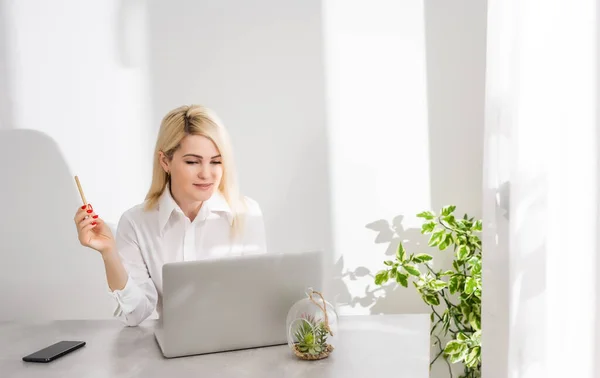 Portré egy üzletasszonyról, aki laptopot használ az irodában egy fehér falnak támasztva. — Stock Fotó