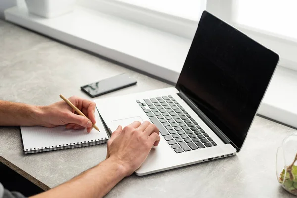 Glimlachende jonge man freelancer met behulp van laptop, online studeren, werken vanuit huis, gelukkig casual man typen op pc notebook surfen internet, genieten van verre baan, zitten aan tafel. — Stockfoto