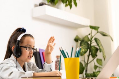 İnternette çocuk. Küçük bir kız bilgisayarda görüntülü konuşma yaparak evde otururken iletişim kuruyor..