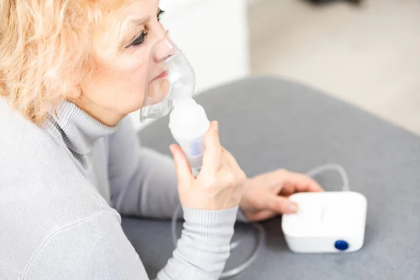 Donna anziana che utilizza macchina asma su sfondo chiaro — Foto Stock