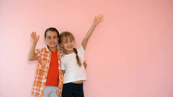 Dos chicas felices abrazándose aisladas sobre fondo rosa — Foto de Stock