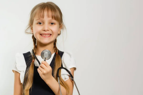 Маленькая школьница изучает медицину с помощью фонендоскопа, изолированного по белому — стоковое фото