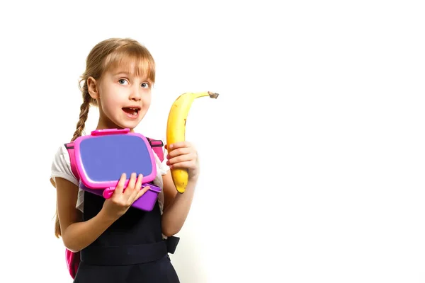Leerlingen van de lagere school met lunchdozen in handen. Meisjes met rugzakken eten fruit. Begin van de lessen. Eerste herfstdag. — Stockfoto