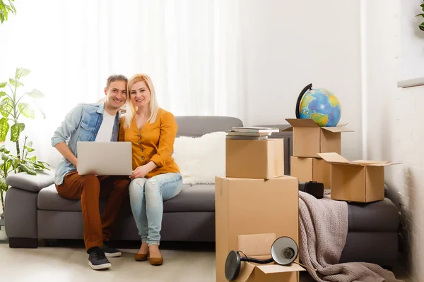 Piękna para siedzi między wieloma pudełkami w swoim nowym domu — Zdjęcie stockowe