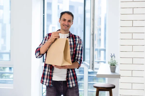 Entrega, correio e conceito de pessoas - homem feliz entregando alimentos em saco de papel descartável para casa do cliente — Fotografia de Stock