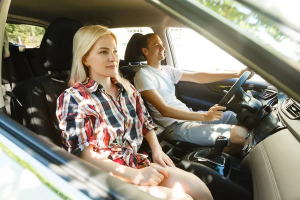 Feliz joven hombre y mujer en un coche disfrutando de un viaje por carretera en un día de verano. —  Fotos de Stock