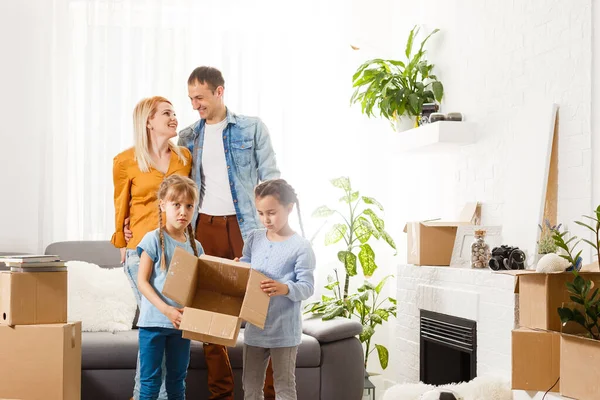 Ευτυχισμένη οικογένεια με χαρτόκουτα σε νέο σπίτι την ημέρα μετακόμισης. — Φωτογραφία Αρχείου