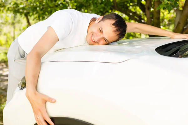 Man hugging on a car in a car dealership — Stock Photo, Image