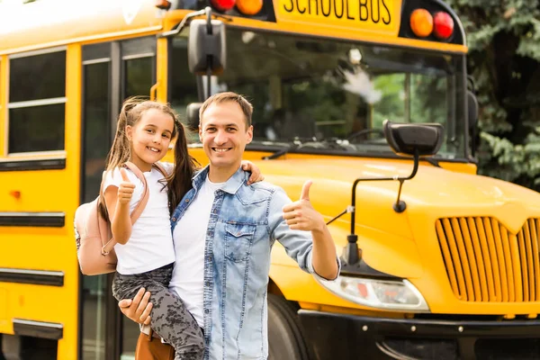 Dívka s otcem se vrací do školy poblíž školního autobusu — Stock fotografie