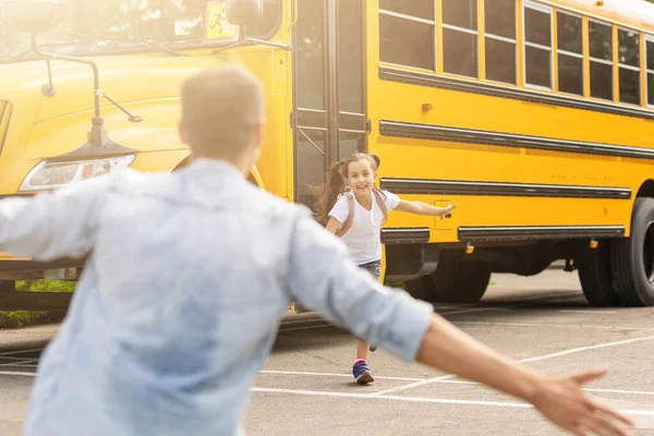 Padre che incontra la figlioletta che esce dallo scuolabus — Foto Stock
