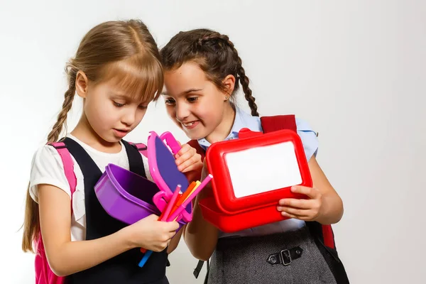 Alunos da escola primária com lancheiras nas mãos. Meninas com mochilas estão comendo frutas. Início das lições. Primeiro dia de queda. — Fotografia de Stock