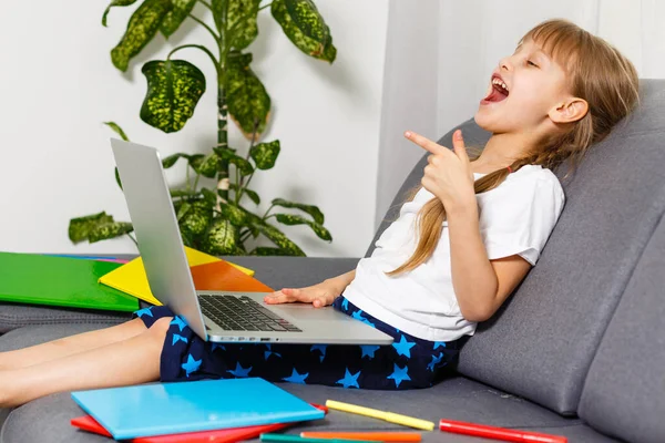 Foto de la pequeña alumna bonita escuela dama encienda el portátil skype lección en línea mantenga libro abierto respuesta lista profesor preguntas sentarse sofá distancia cuarentena estudio comodidad habitación interior — Foto de Stock