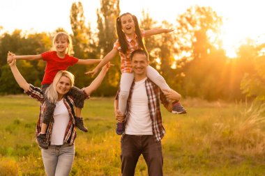 Mutlu aile tarlada yürüyor ve gün batımını seyrediyor.