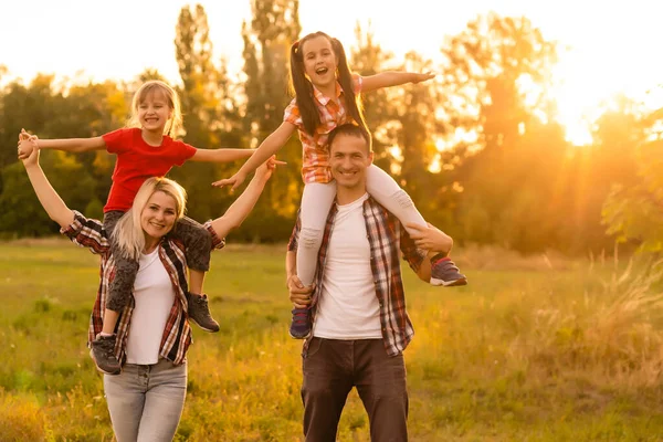 Mutlu aile tarlada yürüyor ve gün batımını seyrediyor. — Stok fotoğraf