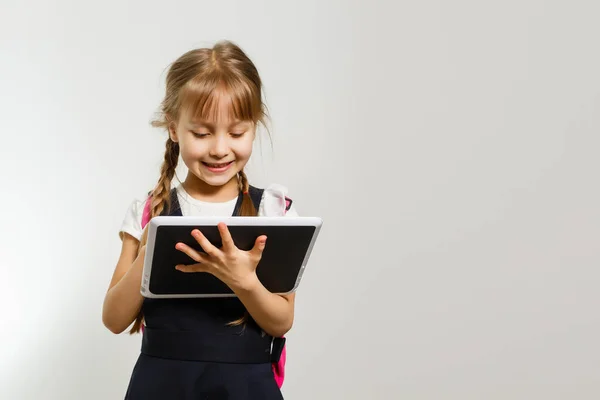 Malá dívka pomocí tabletu na bílém pozadí zdi — Stock fotografie