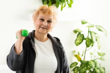 Evde jimnastik. Oturma odasında Dambıllı Pozitif Yaşlı Kadın Eğitimi, Boşluğu Kopyala