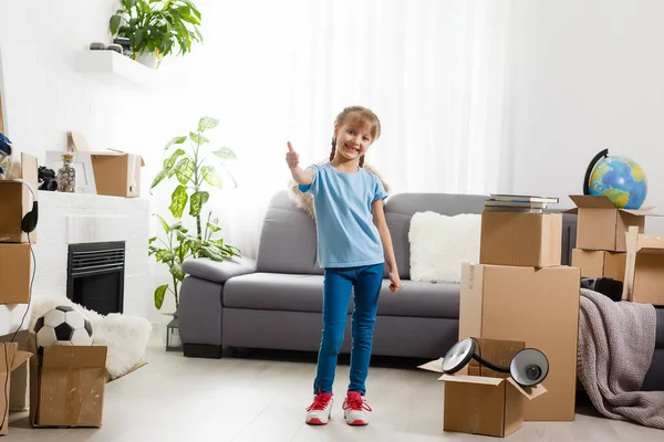 Klein meisje verhuist naar nieuw huis, vlakbij kartonnen doos. — Stockfoto