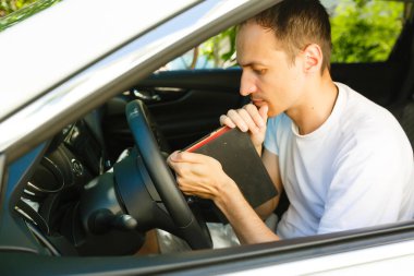 Adam arabada İncil 'le dua ediyor.