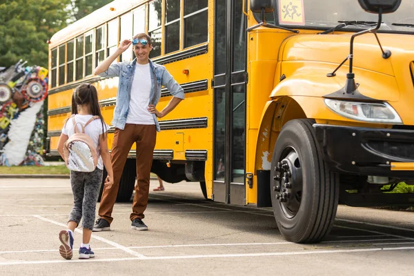 Smiling bus driver looking at camera outside the elementary school