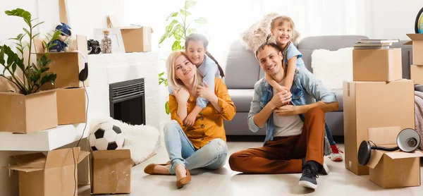 Familia feliz con cajas de cartón en casa nueva en el día de mudanza. —  Fotos de Stock