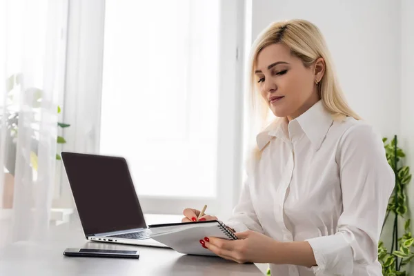 Retrato de uma mulher de negócios usando laptop no escritório contra uma parede branca — Fotografia de Stock